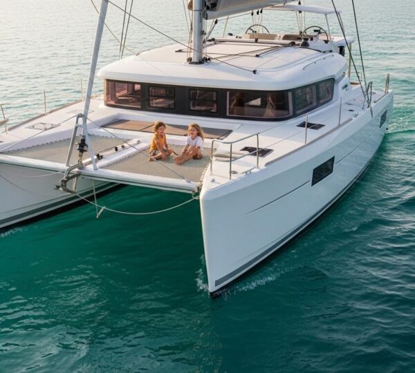 Deux enfants rient sur le pont d'un catamaran stable en pleine mer, illustrant la sécurité et le confort du multicoque.